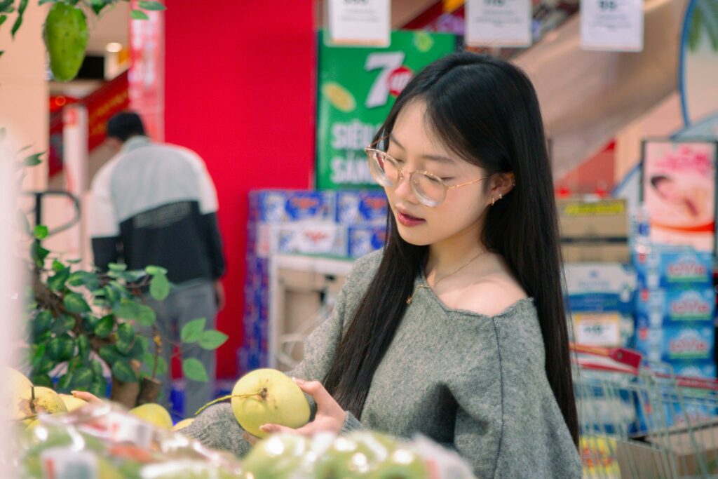 A young woman selecting fresh apples in a vibrant supermarket setting, depicting daily shopping activities.